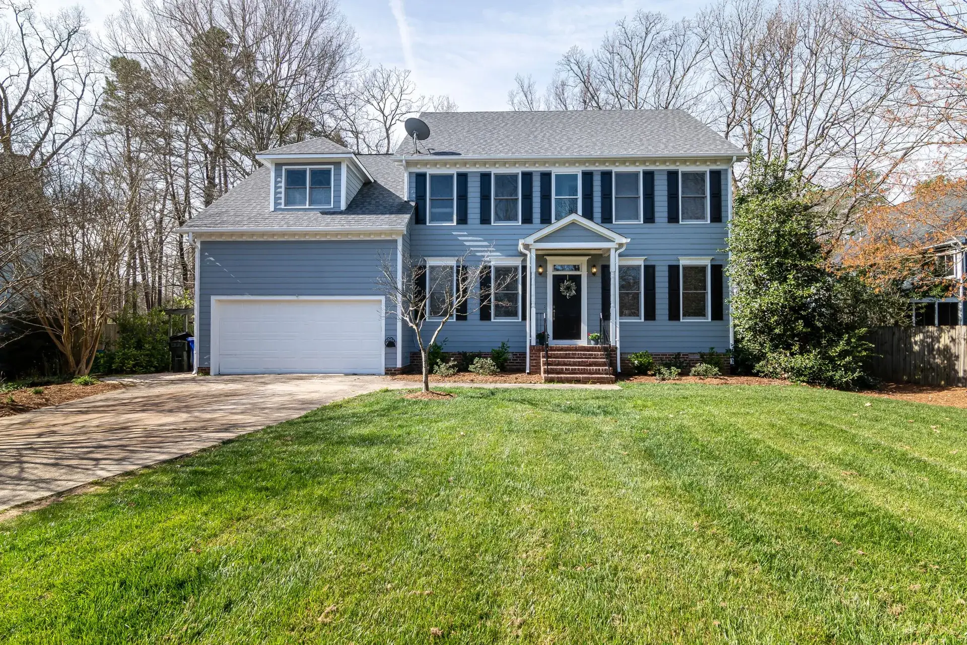 Front yard of a two-story home with a freshly mowed lawn.