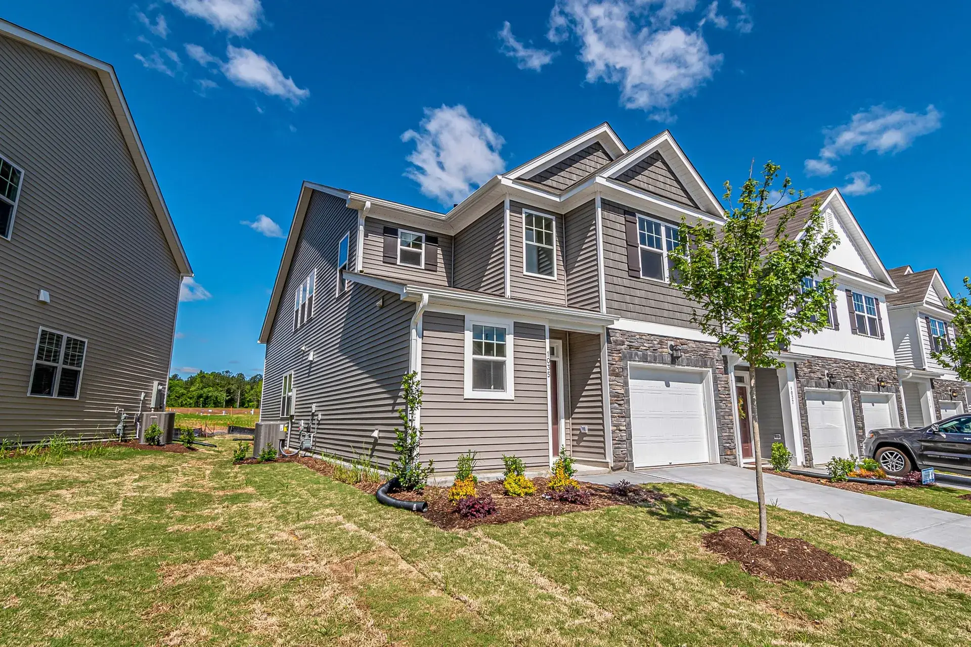 Front yard of a gray two-story home with a fresh lawn.