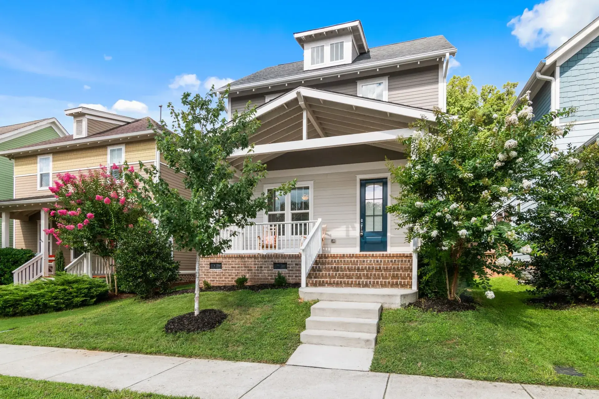 Mowed front lawn and walkway of a home with a porch.