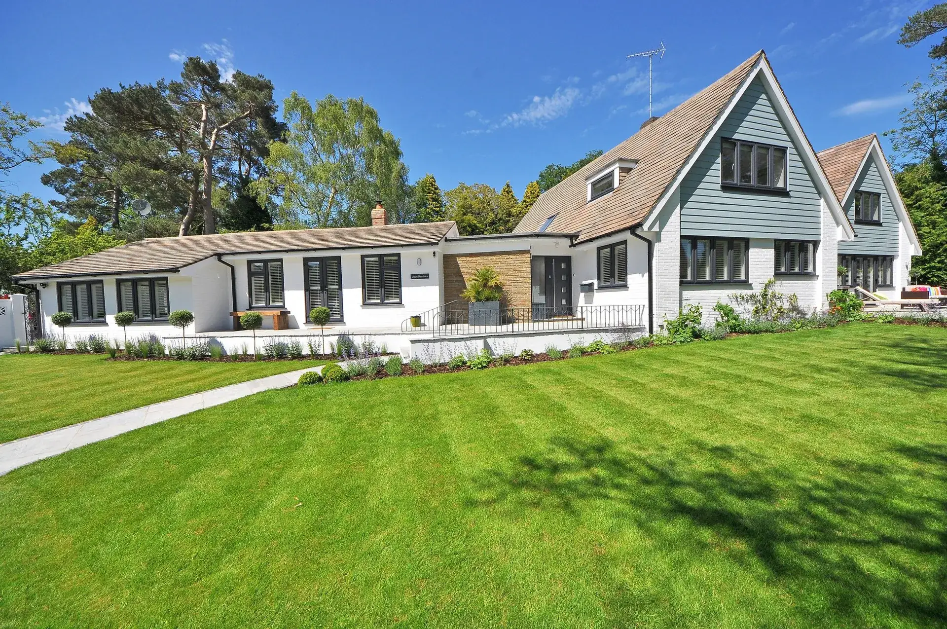 Striped lawn in front of a white home with landscaped beds.